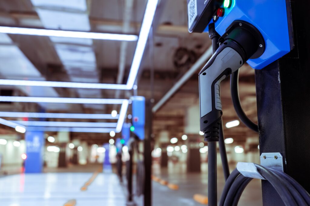 Electric car charging station for charge EV battery. Plug for vehicle with electric engine. EV charger. Clean energy. Charging point at car parking lot. Green power. Future transport technology.